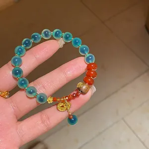 Detailed view of a New Chinese style agate and jade beaded bracelet with gold charms