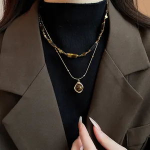 Detail of retro double-layered necklace with Tiger Eye stones on a stylish brown blazer.