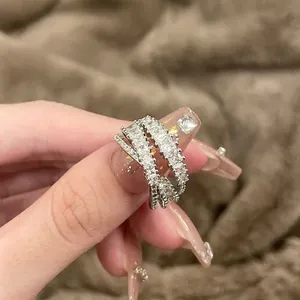 Elegante zilveren crossover ring met fonkelende zirkonia op een zachte bruine ondergrond