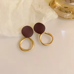 Close-up detail of stylish brown circular studs with golden twisted hoop earrings