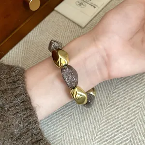 Primo piano di un bracciale elastico in acrilico vintage con perline dorate e marroni