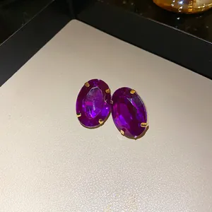 Close-up of vintage oval purple crystal stud earrings with gold claw setting