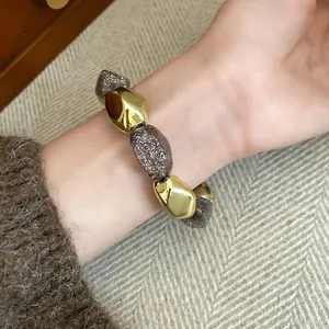 Dettaglio di un braccialetto vintage con perle metalliche dorate e perle acriliche brillanti