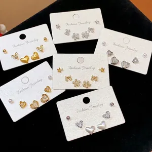 Elegant 18K gold plated stud earrings set with zircon, pearls, and bows on cards.
