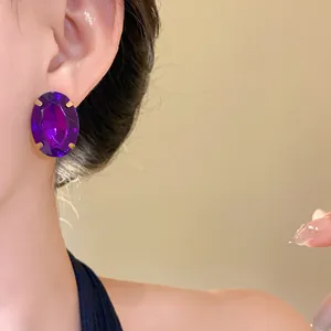 Close-up of elegant oval purple crystal stud earrings worn on an Asian model's ear