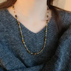 Detailed view of vintage tiger's eye bead necklace worn over a grey knit sweater.