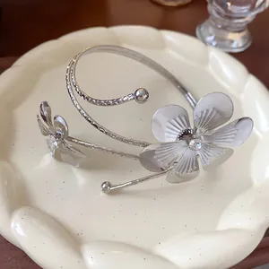 Dettaglio di un bracciale da braccio floreale argento con strass su un piatto decorativo.