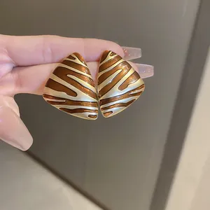 Macro view of vintage triangle earrings featuring a brown and gold zebra pattern