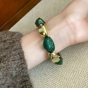 Primo piano di un bracciale elastico retrò in acrilico con glitter verdi e perle dorate