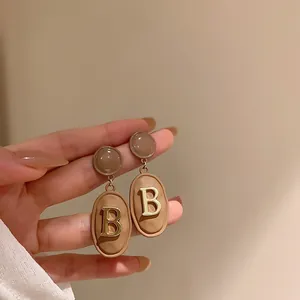 Gros plan sur des boucles d'oreilles vintage marron avec détail de lettre B.