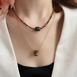 Detail showing layered vintage tiger eye bead and round ball pendant necklaces