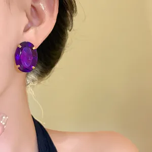 Close-up of vintage-style oval purple gemstone earring with gold prongs on model's ear