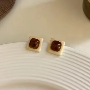 Détail de boucles d'oreilles en résine marbrée marron vintage avec cadre crème