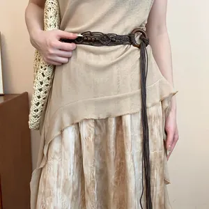 Detail view of a Bohemian braided hemp belt with wooden beads on a beige dress.
