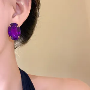 Close-up of a large oval purple gemstone stud earring worn on a model's ear
