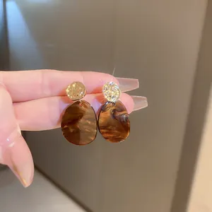 Gros plan détaillé de boucles d'oreilles vintage en marbre brun et clous dorés
