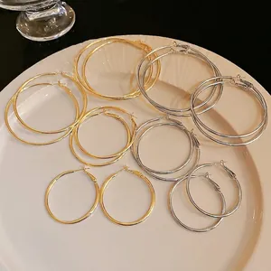 Elegant variety set of gold and silver hoop earrings in multiple sizes on white plate
