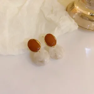 Close-up of Maillard style brown resin drop earrings with marbled white sphere beads