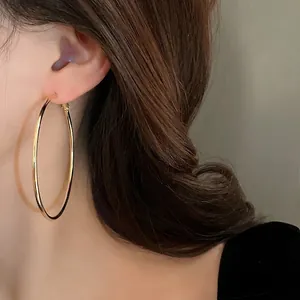 Minimalist gold large hoop earrings for women with elegant metallic finish on model