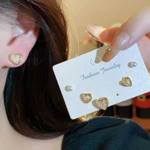 Detail view of heart-shaped 18k gold plated stud earrings with zircons and pearls.