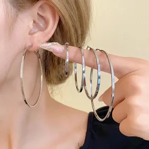 Set of minimalist high-shine silver hoop earrings in multiple sizes on model's ear