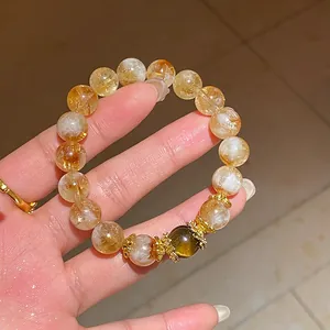 Primo piano dettagliato di un bracciale di citrino con ciondoli dorati e perla occhio di tigre