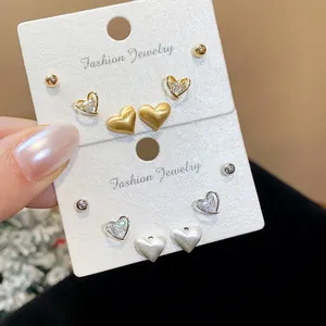 Close-up of heart-shaped stud earring sets in gold and silver finishes with zircons