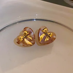Vue détaillée de boucles d'oreilles cœur en marbre café vintage avec nœuds dorés