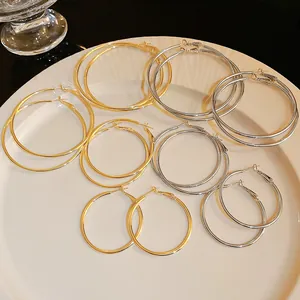 Variety of polished metal hoop earrings in gold and silver finishes on a white plate.