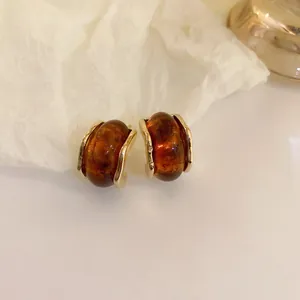 Detail view of vintage amber brown resin C-shaped earrings with gold frame