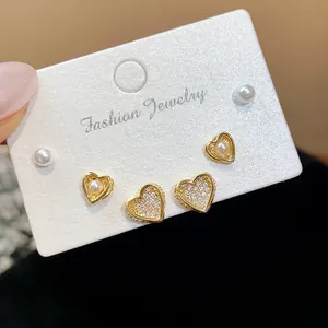 Detailed view of heart-shaped gold plated stud earrings with zircons and pearls