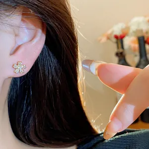Close-up view of an elegant 18k gold plated flower stud earring with sparkling zircons on ear