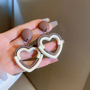 Détail de boucles d'oreilles vintage en forme de cœur marron et crème pour l'hiver