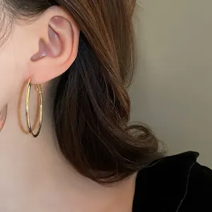 Close-up detail of a classic gold hoop earring worn by a model with a minimalist style