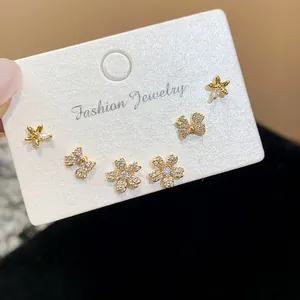 Detail of gold-plated earring set featuring zircon-paved star, bow, and flower studs
