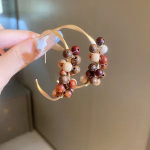 Gros plan détaillé de boucles d'oreilles créoles rétro avec des perles en bois brunes.