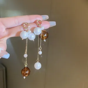 Gros plan détaillé de boucles d'oreilles pendantes en ambre et perles blanches avec chaînes