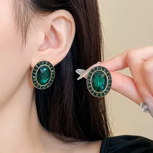 Detaillierte Ansicht von smaragdgrünen ovalen Ohrsteckern im Vintage-Stil mit Goldakzenten