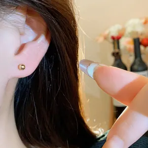 Close-up detail of a minimalist 18k gold plated ball stud earring worn on an earlobe