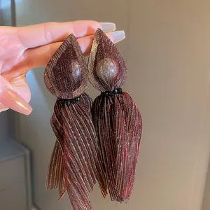 Gros plan de boucles d'oreilles vintage marron chatoyantes avec une texture plissée unique.
