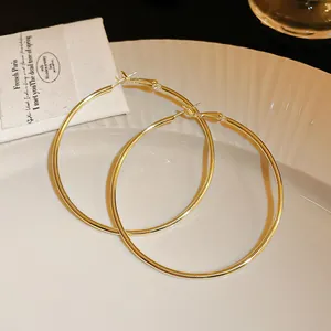 Close-up of oversized gold-tone minimalist hoop earrings on a white elegant plate