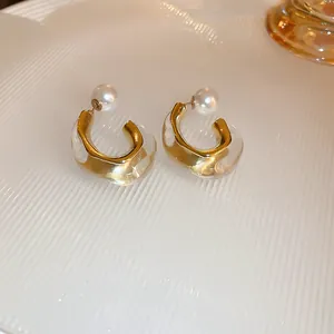 Détail de boucles d'oreilles vintage en résine dorée avec perles blanches