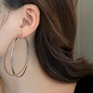 Close-up detail of minimalist large silver metal hoop earrings on female model's ear
