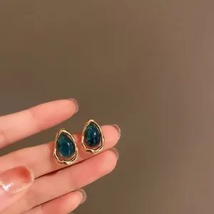 Détail de boucles d'oreilles vintage avec goutte d'eau bleu foncé et cadre doré.