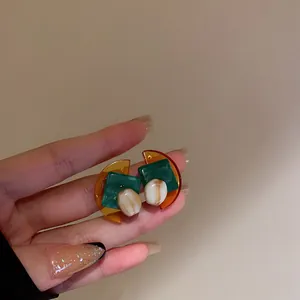 Vue détaillée de boucles d'oreilles géométriques vintage aux accents vert émeraude et ambre