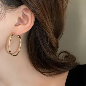 Close-up of minimalist large gold hoop earring on a model with elegant brown hair