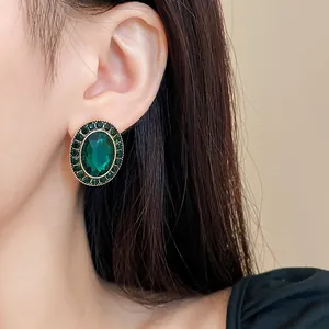 Detailaufnahme eines grünen Kristallohrrings im Vintage-Stil, der am Ohr getragen wird