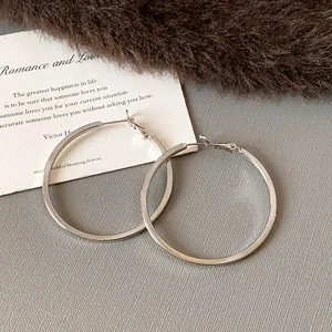 Close-up detail of large silver hoop earrings with elegant polished finish.