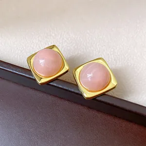 Vue détaillée de boucles d'oreilles carrées roses de style vintage avec monture dorée