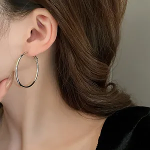 Close-up detail of a large minimalist silver hoop earring worn on a model's ear
